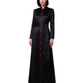 A woman modeling a long black satin-like robe with red button accents and red piping details, photographed against a plain white background.