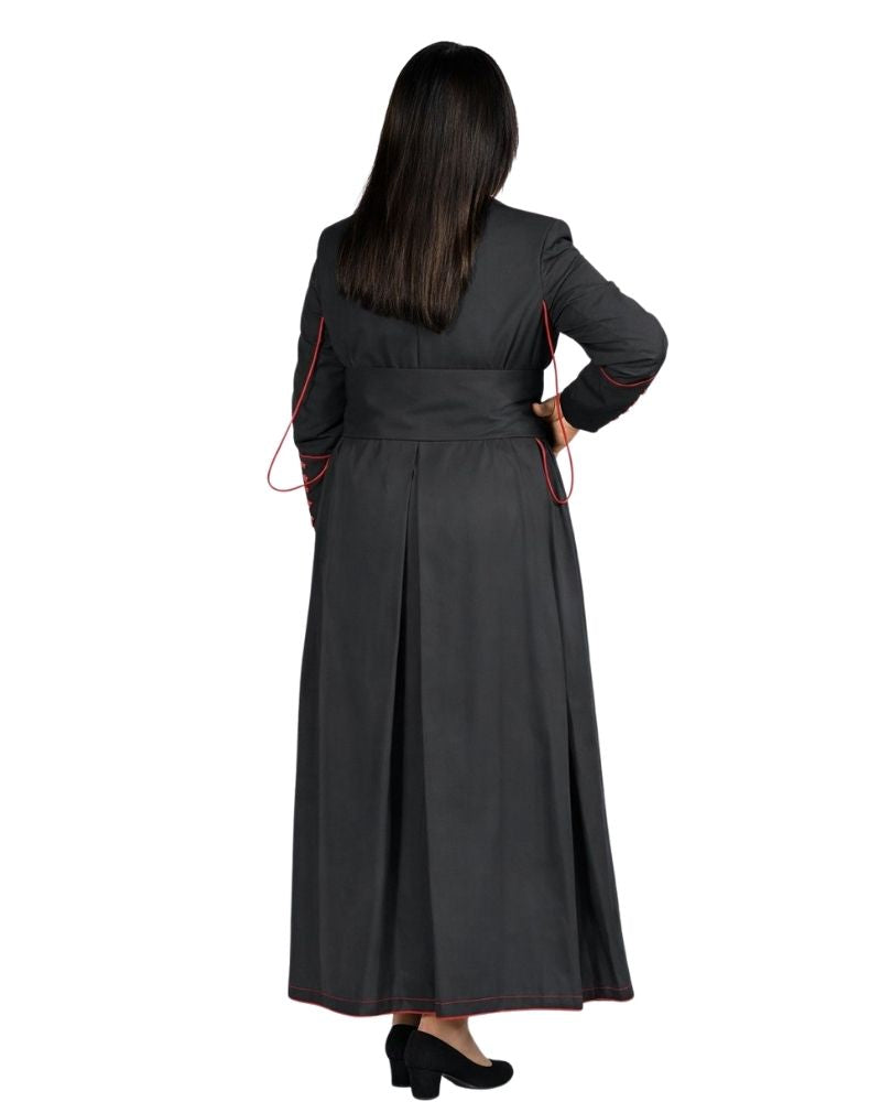A woman shown from the back wearing a long cassock with thin red piping along the sleeves and side seams, photographed against a plain white background.