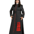 A woman modeling a long black cassock with red trim, red decorative buttons, and a red fringed detail on the front, set against a plain white background.