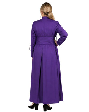 Woman wearing a long purple cassock with a white collar on a white background.