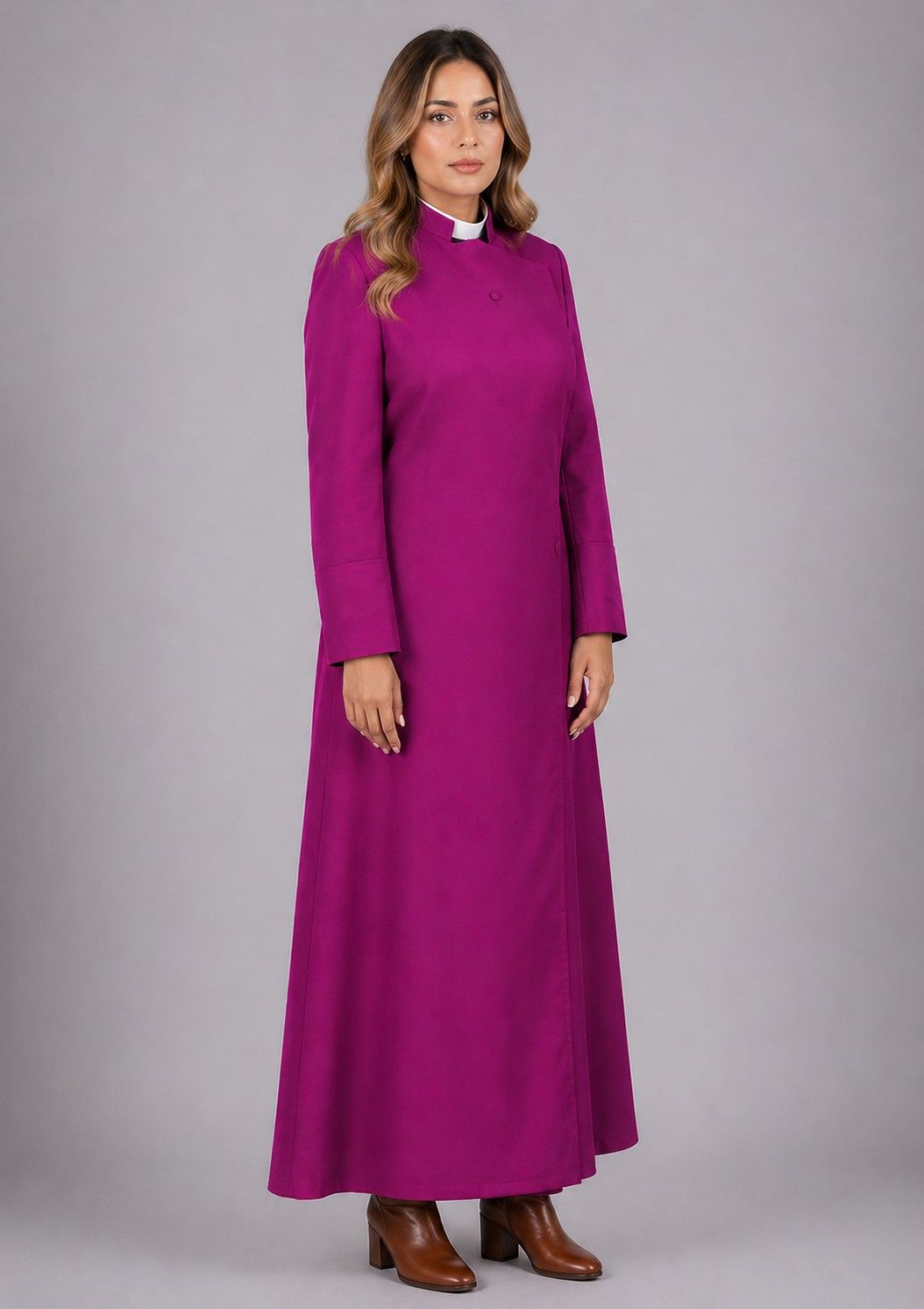 Woman wearing a long purple dress with a high collar against a gray background