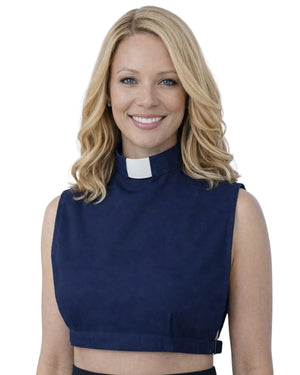A smiling woman wearing a navy blue sleeveless mock-neck top with a white clerical collar, shown against a plain white background.