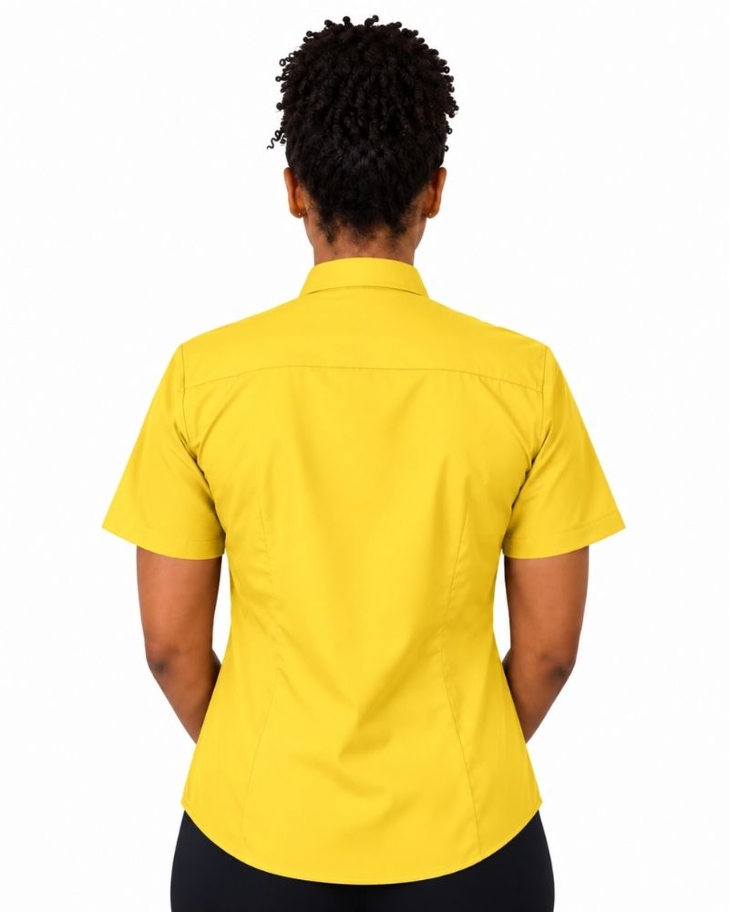A woman viewed from the back wearing a bright yellow short-sleeve clerical shirt and black bottoms, against a plain white background.