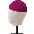 A clergy zucchetto cap displayed on a mannequin head stand. The top half of the cap is a deep magenta-purple, and the bottom half is a light beige heather fabric.