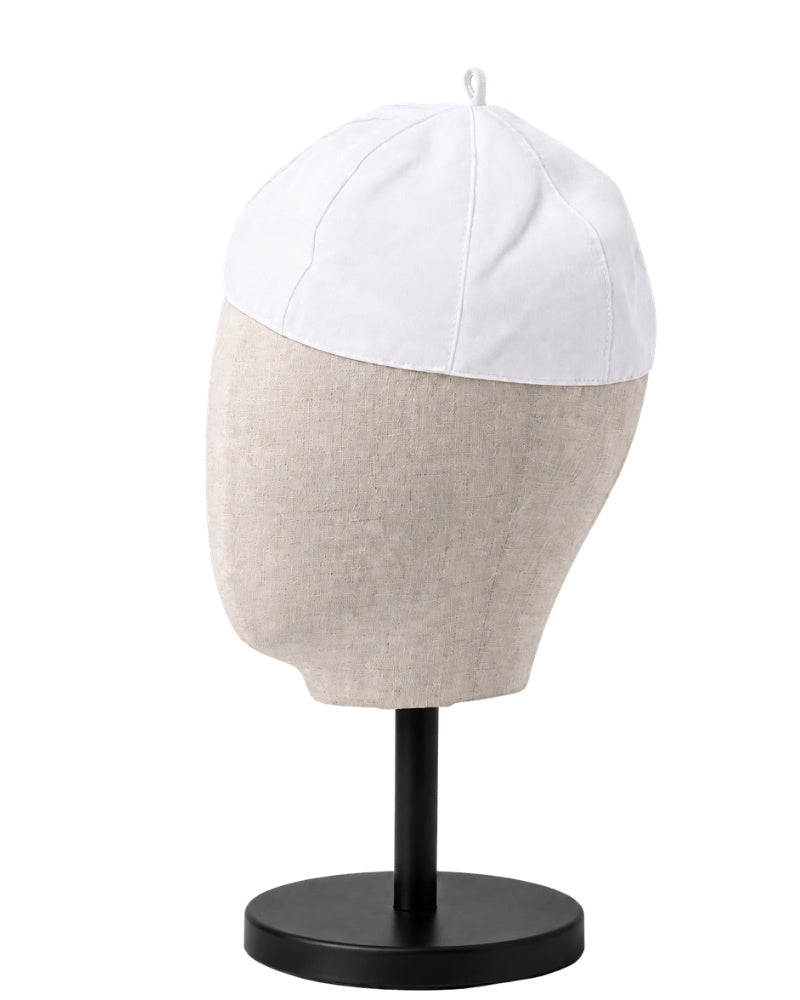 A clergy zucchetto cap with a white top panel and a light beige textured lower section, displayed on a black mannequin head stand against a white background.
